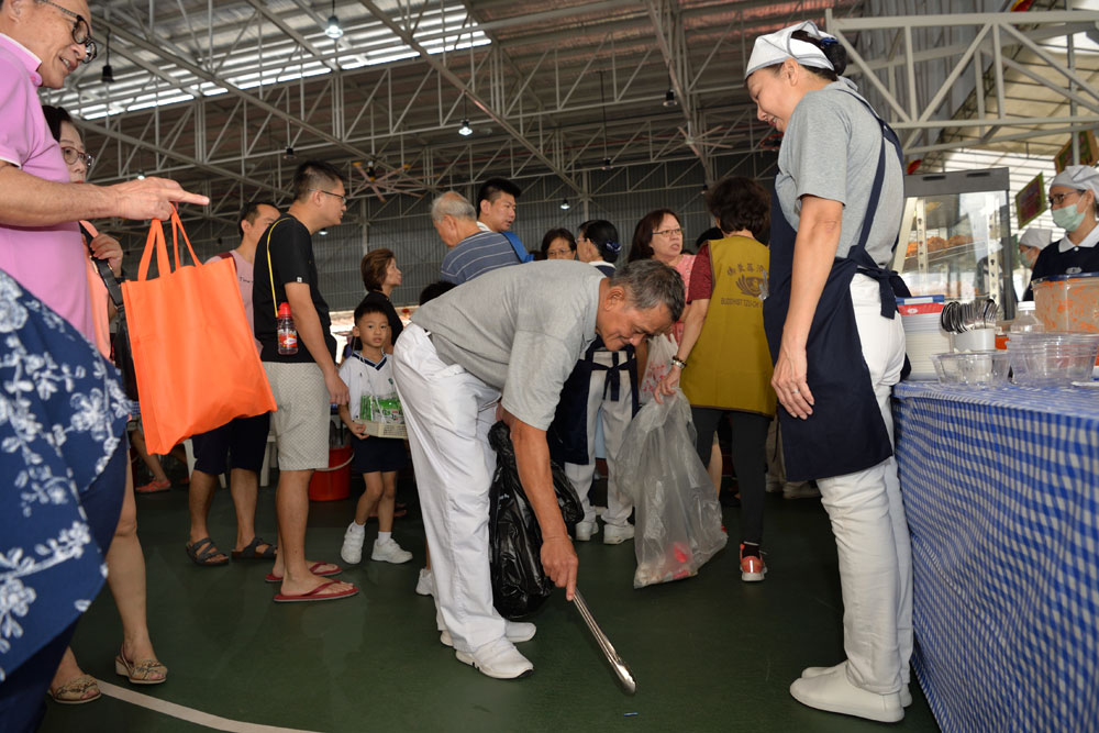 志工捡起地上的垃圾，然后再进行分类。摄 / 蔡佑良
