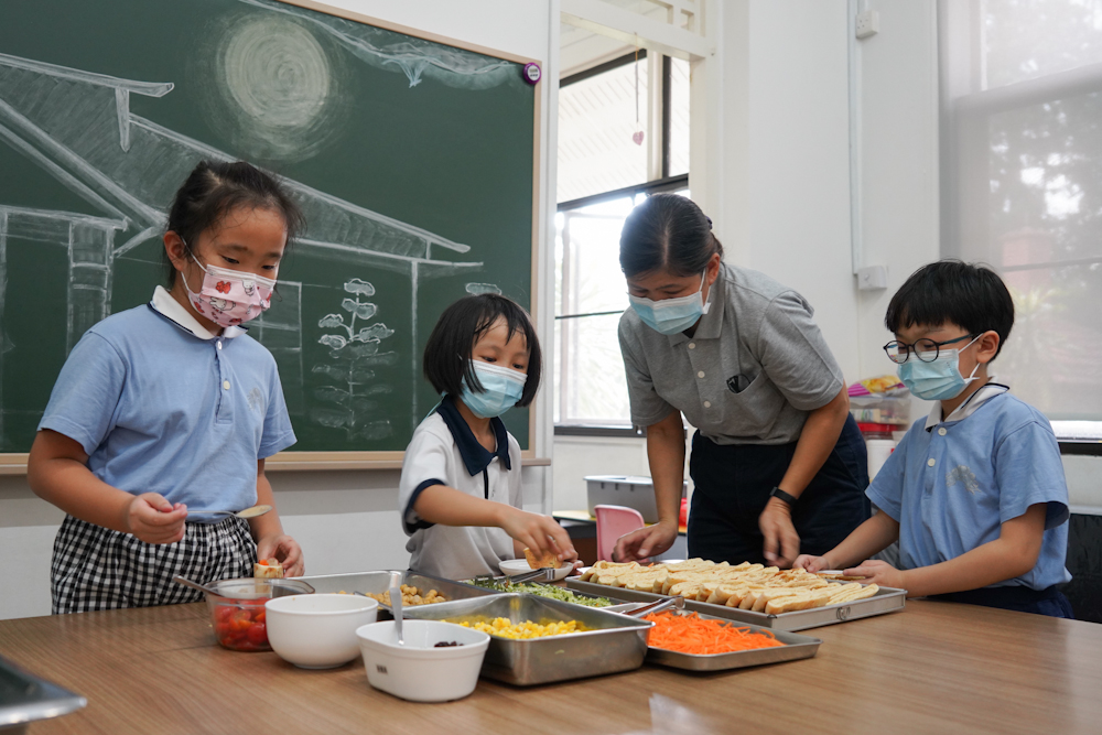 在安亲班经理林秀莉的协助下，学生学习如何准备口袋沙拉。 （摄/曾美珍）